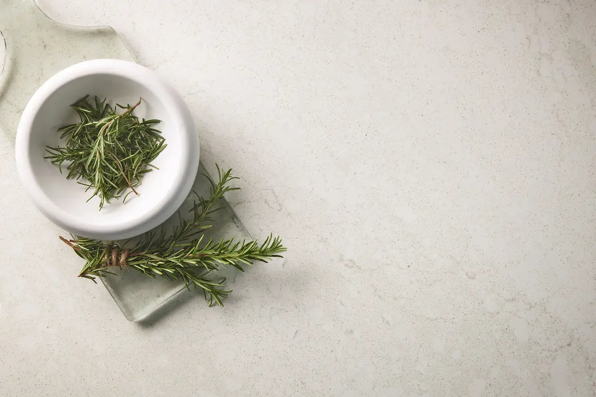 White bowl with green herbs on a light gray surface