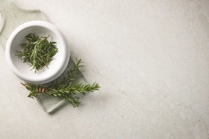 White bowl with green herbs on a light gray surface